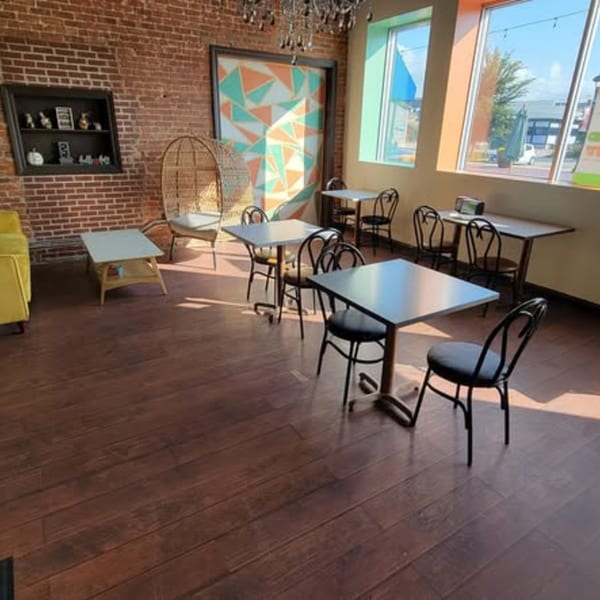 Uplifted Bistro's cafe interior with brick walls, wooden floors, tables, chairs, and large windows.