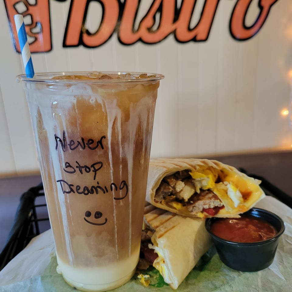 Iced coffee with "Never Stop Dreaming" and a breakfast burrito with salsa at Uplifted Bistro.