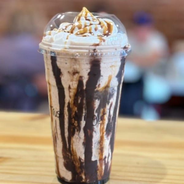 Uplifted Bistro's chocolate and caramel milkshake with whipped cream on a wooden table.