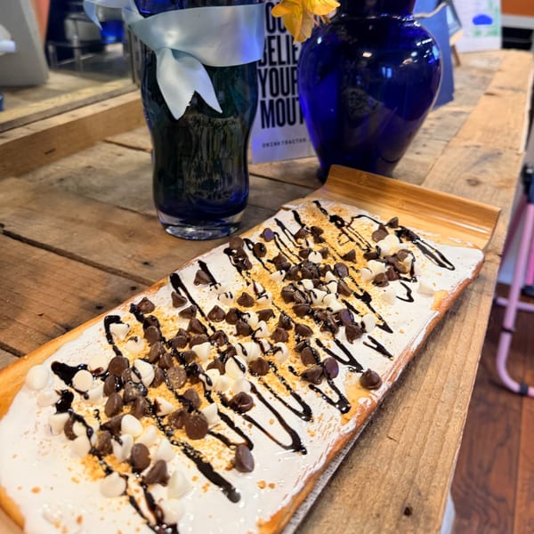 A s'mores flatbread with chocolate and white chocolate chips, graham cracker crumbs, and chocolate drizzle.