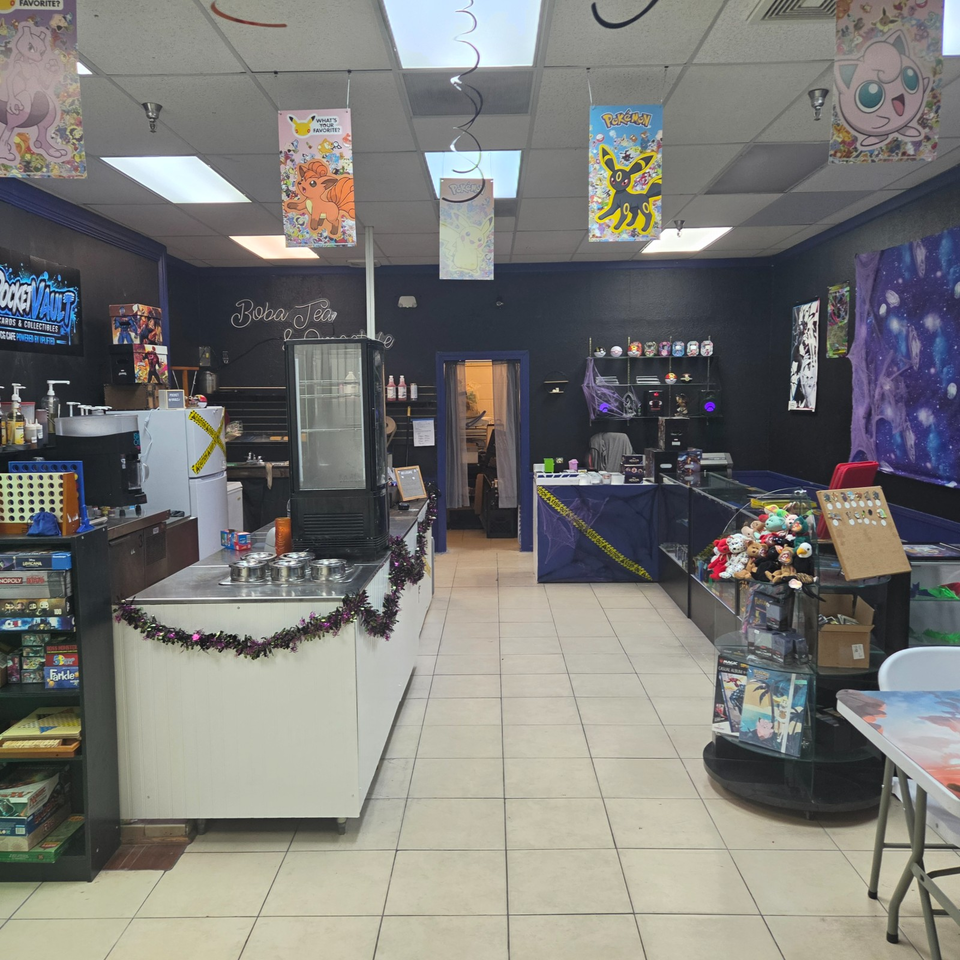 Colorful boba tea and trading card shop interior with Pokémon decorations, game displays, plush toys, and a beverage counter.
