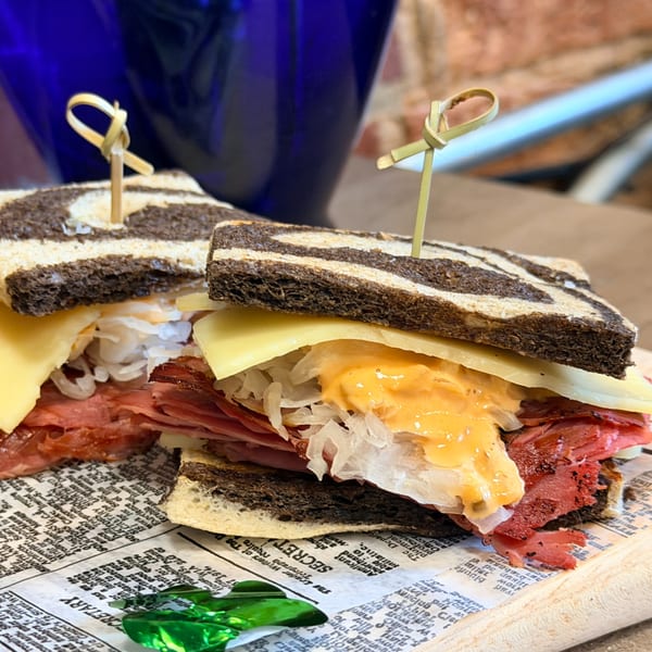 Two Uplifted Bistro Reuben sandwiches with marbled rye, corned beef, Swiss, sauerkraut, and Russian dressing.
