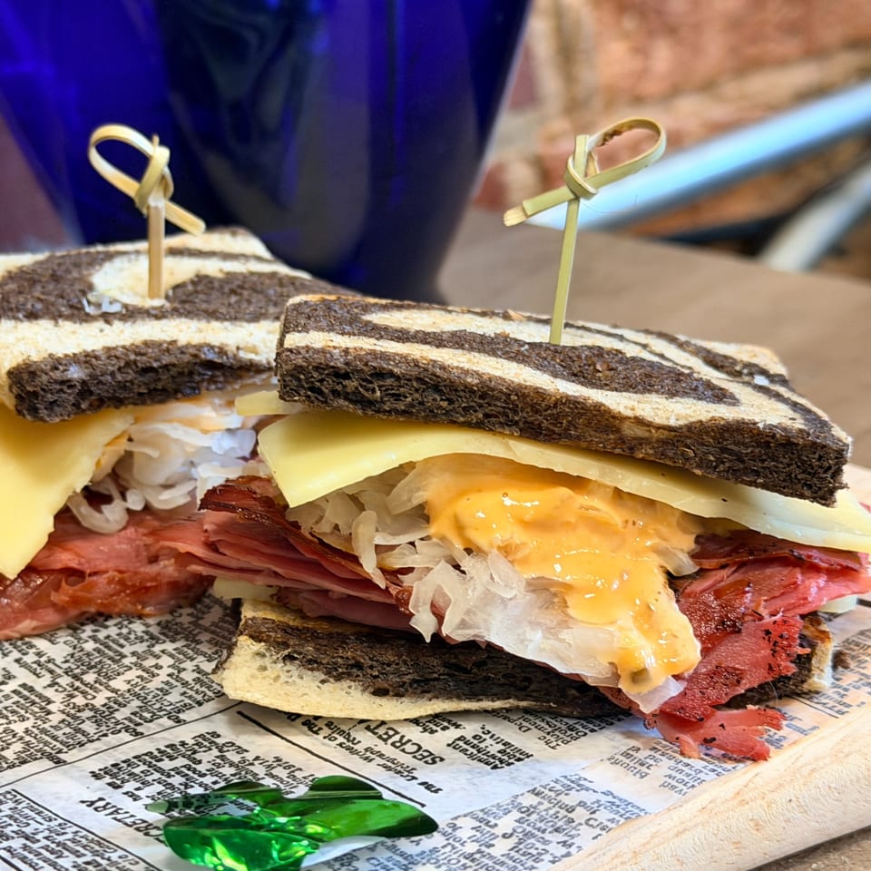 Two Uplifted Bistro Reuben sandwiches with marbled rye, corned beef, Swiss, sauerkraut, and Russian dressing.