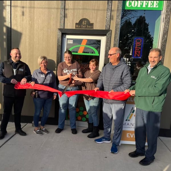 Six people, including Uplifted Bistro staff, participate in a ribbon-cutting ceremony outside the cafe.
